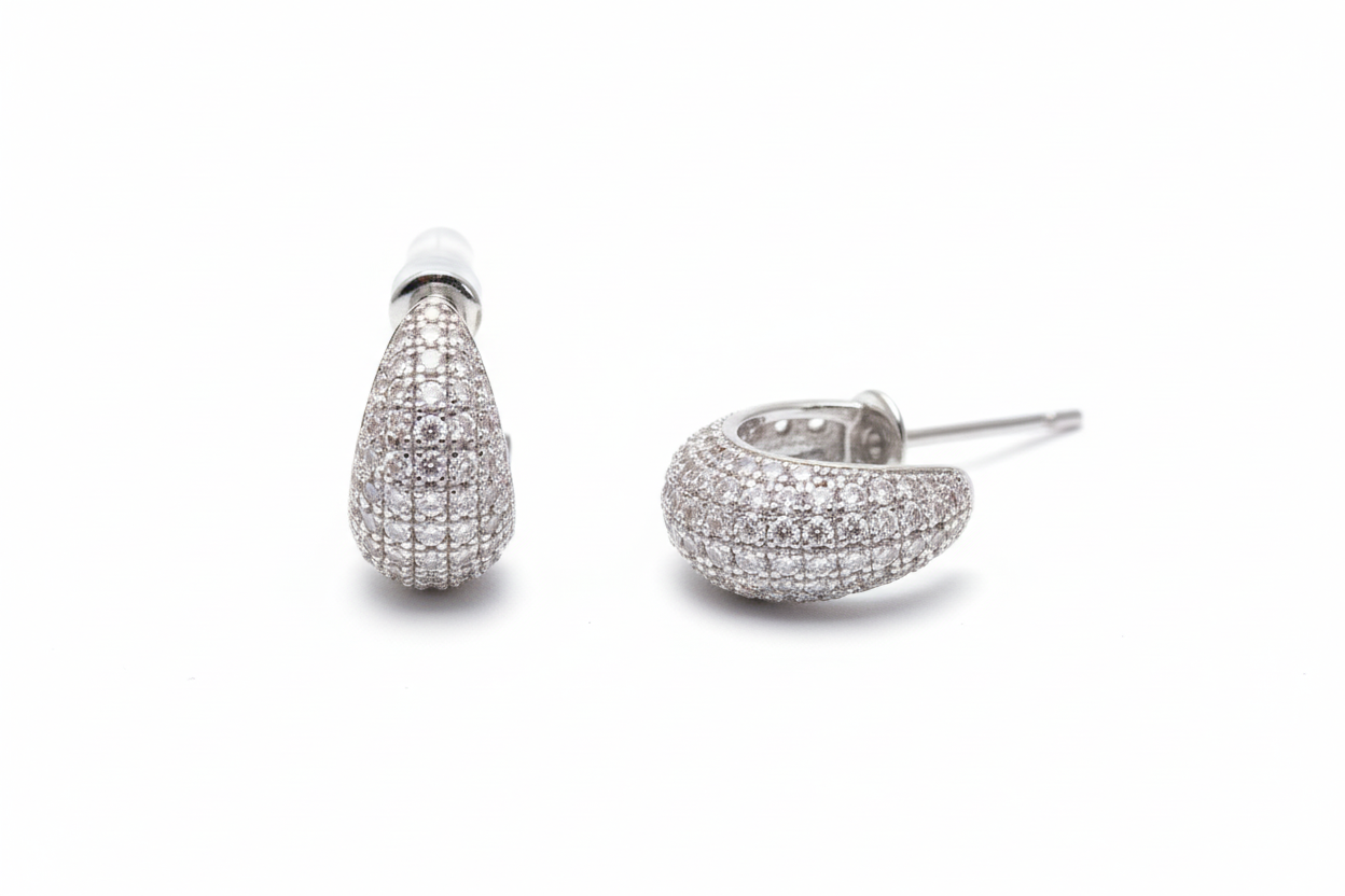 Silver glittery crescent moon earrings on a light gray fabric background